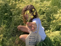 Young woman holding yellow flowers in a field, capturing a feminine and natural aesthetic, reflecting themes of femininity.